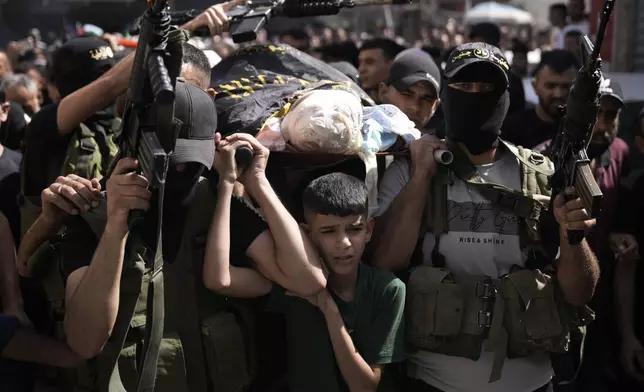 Gunmen march with the body of Mustafa Zakarneh, draped the Islamic Jihad militant flag during the funeral for three Palestinian militants killed in an Israeli military operation in the West Bank town of Qabatiya, Friday, Sept. 20, 2024. (AP Photo/Majdi Mohammed)