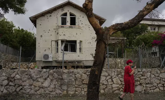 A woman walks past a house hit by a rocket fired from Lebanon, in Moreshet, northern Israel, on Sunday, Sept. 22, 2024. (AP Photo//Ariel Schalit)