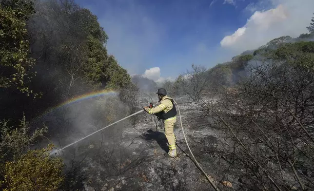 An Israeli firefighter works to extinguish a fire after a rocket fired from Lebanon hit an open field in northern Israel, Wednesday, Sept. 18, 2024. (AP Photo/Baz Ratner)