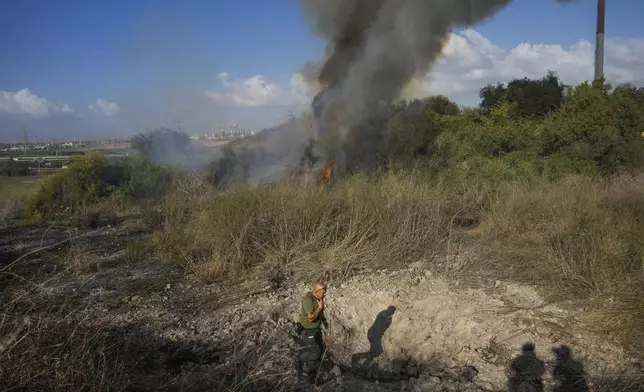 A police officer inspects the area around a fire after the military said it fired interceptors at a missile launched from Yemen that landed in central Israel on Sunday, Sept. 15, 2024. (AP Photo/Ohad Zwigenberg)