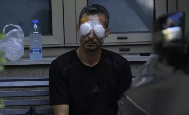 A man who was injured in the explosion of one of the handheld devices, sits outside the Eye Specialist hospital, in Beirut, Lebanon, Friday, Sept. 20, 2024. (AP Photo/Hussein Malla)