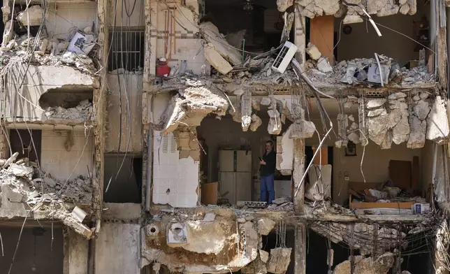 A man watches rescuers sift through the rubble as they search for people still missing at the site of Friday's Israeli strike in Beirut's southern suburbs, Monday, Sept. 23, 2024. (AP Photo/Hassan Ammar)