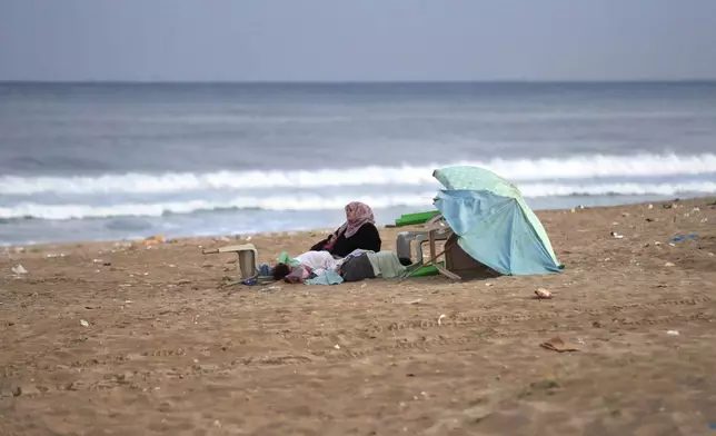 A Lebanese woman who fled the southern villages amid ongoing Israeli airstrikes Monday, settles with her kids on a public beach in the southern port city of Sidon, Lebanon, Tuesday, Sept. 24, 2024. (AP Photo/Mohammed Zaatari)