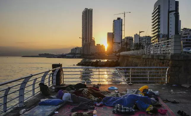 Families sleep on Beirut's corniche after fleeing the Israeli airstrikes in Beirut's southern suburb, Lebanon, Monday, Sept. 30, 2024. (AP Photo/Hassan Ammar)