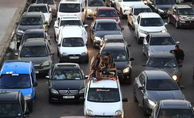 Lebanese citizens who fled the southern villages amid ongoing Israeli airstrikes Monday, sit on their cars at a highway that links to Beirut city, in the southern port city of Sidon, Lebanon, Tuesday, Sept. 24, 2024. (AP Photo/Mohammed Zaatari)