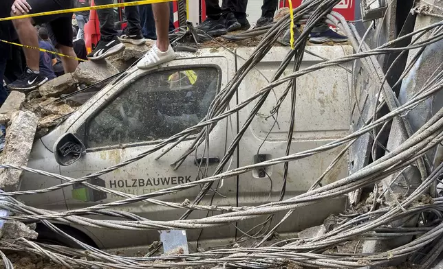 People stand on top of a damaged car at the scene of a missile strike in the southern suburbs of Beirut, Friday, Sept. 20, 2024. (AP Photo/Bilal Hussein)