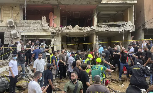 People gather near a damaged building at the scene of an Israeli missile strike in the southern suburbs of Beirut, Friday, Sept. 20, 2024. (AP Photo/Bilal Hussein)