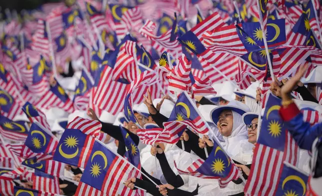 Students wave national flags during the National Day parade in Putrajaya, Malaysia, Saturday, Aug. 31, 2024. (AP Photo/Vincent Thian)