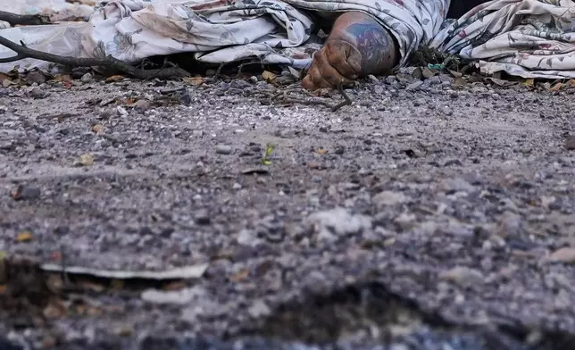 The dead body of man, his arm marked with a tattoo of the Virgin of Guadalupe, lies covered on a street in La Costerita neighborhood of Culiacan, Sinaloa state, Mexico, Thursday, Sept. 19, 2024. (AP Photo/Eduardo Verdugo)