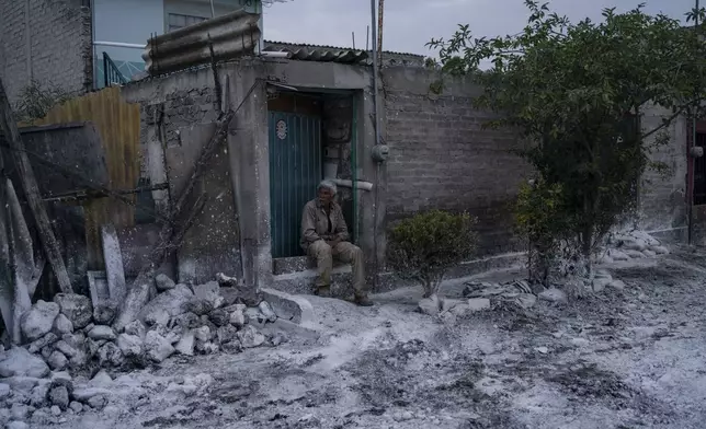 Mario Mata sits outside his home where the street is covered with lime to combat odor and humidity caused by sewage-infused flooding in Valle de Chalco, State of Mexico, Monday, Sept. 9, 2024. (AP Photo/Felix Marquez)