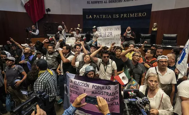 Protesters interrupt a Senate session in which lawmakers were debating the government's proposed judicial reform, which would make judges stand for election, in Mexico City, Tuesday, Sept. 10, 2024. (AP Photo/Felix Marquez)