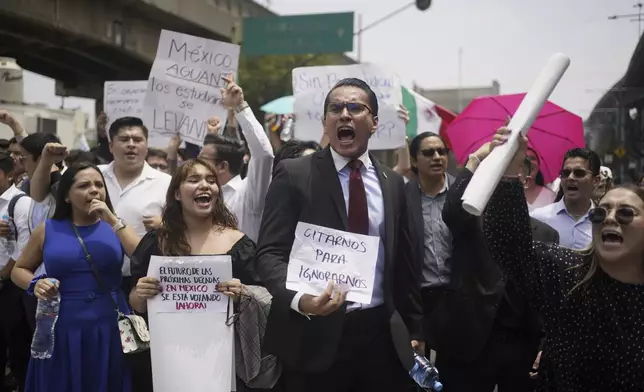 Law students block a street to protest against constitutional reform proposals that would make judges stand for election, outside a sports center where lawmakers are meeting as an alternative due to other demonstrators blocking the Congress building in Mexico City, Tuesday, Sept. 3, 2024. The signs read in Spanish: "Call us to ignore us," and "The future of the next decades in Mexico is being voted on now!" (AP Photo/Felix Marquez)