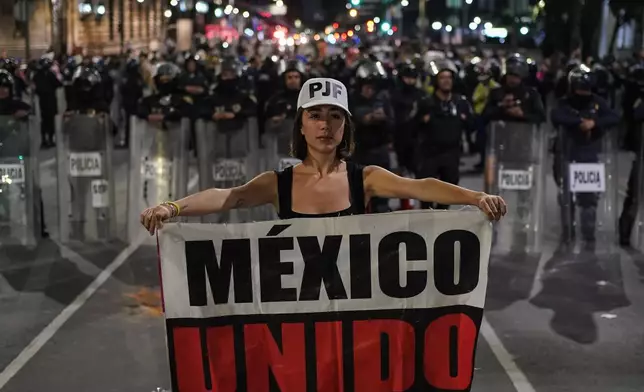 Student Daniela Camberos holds a banner that reads in Spanish "Mexico United" in front of police during a protest against the government's proposed judicial reform, which would make judges stand for election, outside the Senate in Mexico City, Tuesday, Sept. 10, 2024. (AP Photo/Felix Marquez)