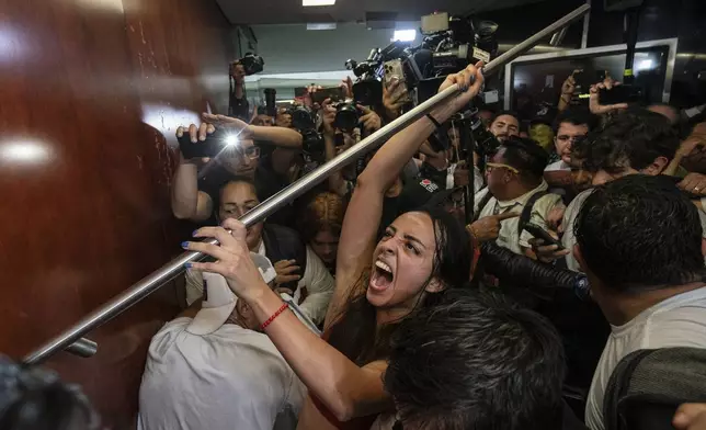 Protesters attempt to break into a room in the Senate as lawmakers weigh the government's proposed judicial reform, which would make judges stand for election, in Mexico City, Tuesday, Sept. 10, 2024. (AP Photo/Felix Marquez)