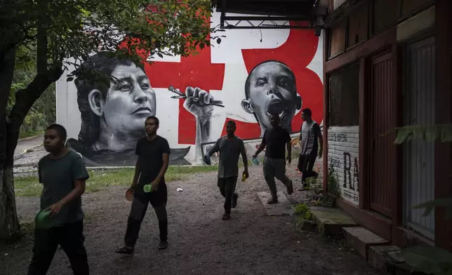 First-year students walk by a mural featuring some of their 43 missing classmates at the Raúl Isidro Burgos Rural Normal School in Ayotzinapa, Guerrero state, Mexico, Sunday, Aug. 25, 2024. (AP Photo/Felix Marquez)