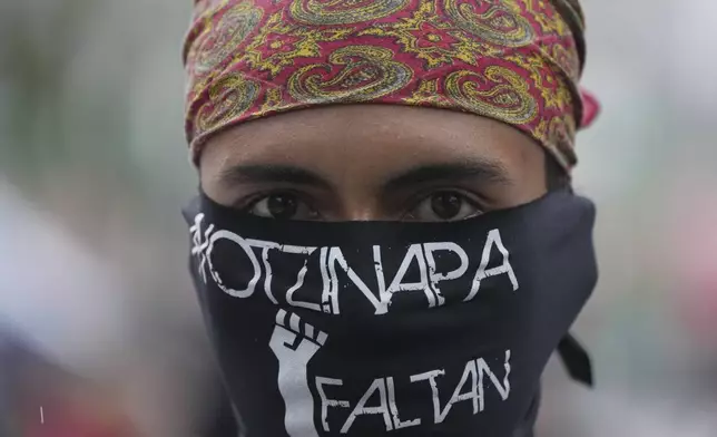 A masked youth takes part in a demonstration marking the 10-year anniversary of the disappearance of 43 students from an Ayotzinapa rural teacher's college, in Mexico City, Thursday, Sept. 26, 2024. (AP Photo/Fernando Llano)