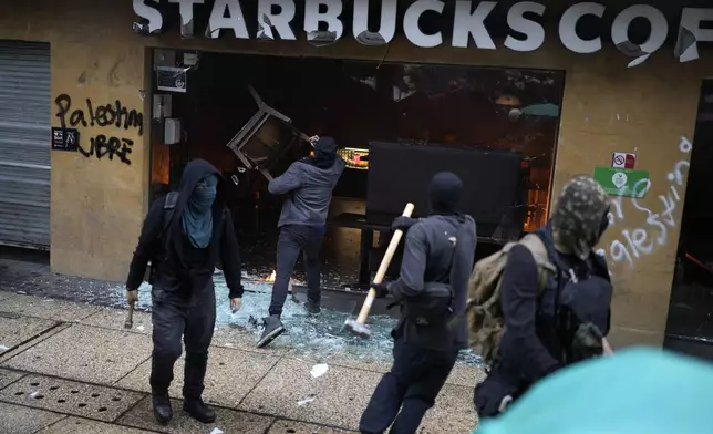 Masked youth destroy a Starbucks storefront during a march marking the 10-year anniversary of the disappearance of 43 students from an Ayotzinapa rural teacher's college, in Mexico City, Thursday, Sept. 26, 2024. (AP Photo/Eduardo Verdugo)