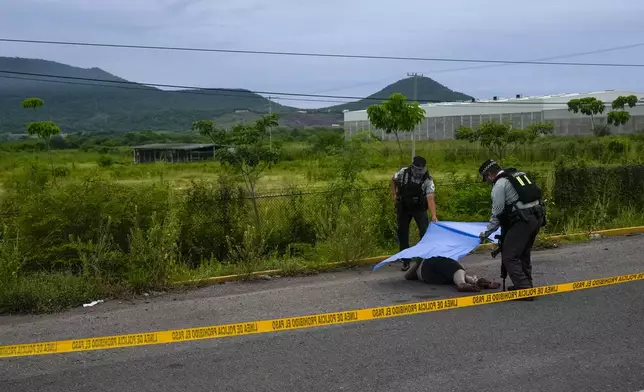 Mexican National Guardsmen cover a body found lying on the side of a road in Culiacan, Sinaloa state, Mexico, Saturday, Sept. 21, 2024. (AP Photo/Eduardo Verdugo)