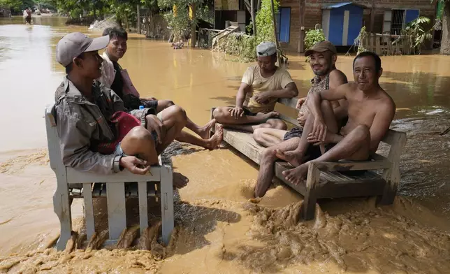 Local residents sit on a bench on a flooded road in Naypyitaw, Myanmar, Saturday, Sept. 14, 2024. (AP Photo/Aung Shine Oo)