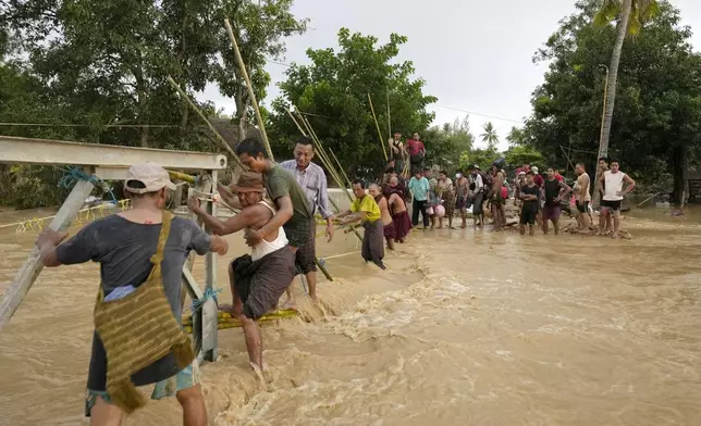 Local residents wade through flooded water at a broken bridge, in Naypyitaw, Myanmar, Tuesday, Sept. 17, 2024. (AP Photo/Aung Shine Oo)