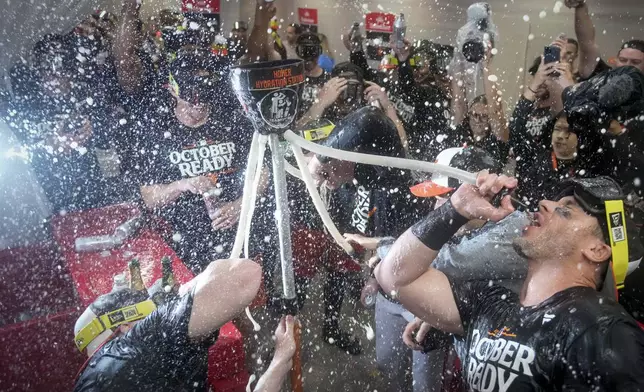 Baltimore Orioles' players drink from the hydration station after clinching a playoff berth by defeating the New York Yankees in baseball game, Tuesday, Sept. 24, 2024, in New York. (AP Photo/Bryan Woolston)