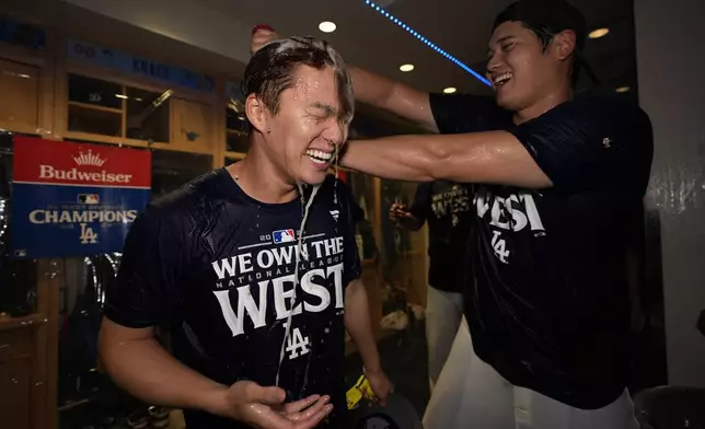 Los Angeles Dodgers designated hitter Shohei Ohtani, right, douses teammate starting pitcher Yoshinobu Yamamoto, left, after the Dodgers defeated the San Diego Padres 7-2 in a baseball game to clinch the National League West division Thursday, Sept. 26, 2024, in Los Angeles. (AP Photo/Ashley Landis)