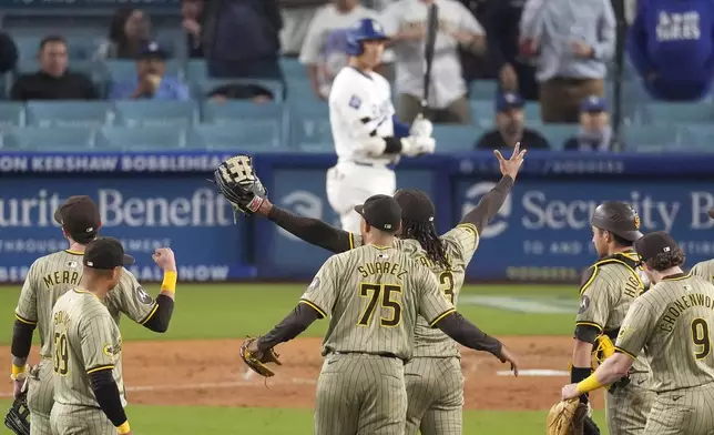 Members of the San Diego Padres celebrate after the Padres clinched a playoff spot with a triple play to end their baseball game as Los Angeles Dodgers' Shohei Ohtani stands at the plate, Tuesday, Sept. 24, 2024, in Los Angeles. (AP Photo/Mark J. Terrill)