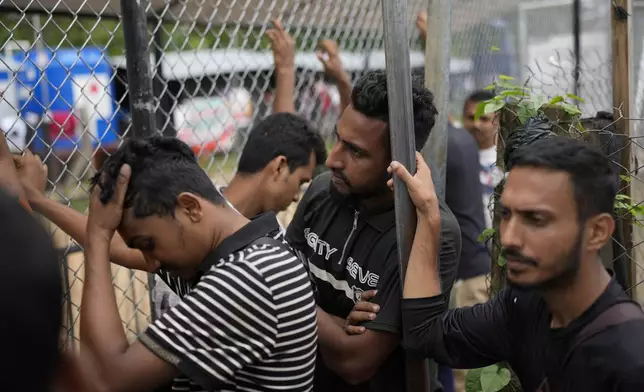 Migrants from Bangladesh wait at an immigration post where Panamanian officers process the identifications of those who have trekked across the Darién Gap, in Lajas Blancas, Panama, Thursday, Sept. 26, 2024. (AP Photo/Matias Delacroix)