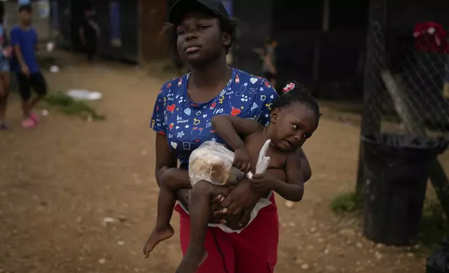 Dorcas Many, from Democratic Republic of the Congo, carries her daughter Maria Many at a camp where migrants who walked across the Darien Gap stop in Lajas Blancas, Panama, Thursday, Sept. 26, 2024. (AP Photo/Matias Delacroix)