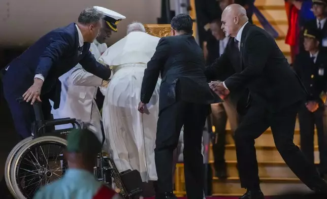 Papua New Guinea's deputy Prime Minister John Rosso, right, and rear-Admiral Philip Polewara, second from left, reach out to help Pope Francis keep his balance during a welcome ceremony at Port Moresby's "Jackson" International Airport, Friday, Sept. 6, 2024. As a second leg of his 11-day trip to Asia and Oceania Pope Francis's visit to Papua New Guinea will take him to a remote part of the South Pacific island nation where Christianity is a recent addition to traditional spiritual beliefs developed over millennia.(AP Photo/Gregorio Borgia)