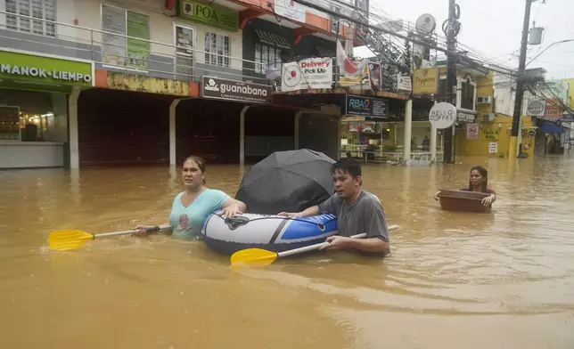 Residents use rubber paddles from a toy boat as they wade along a flooded street caused by heavy rains from Tropical Storm Yagi, on Monday, Sept. 2, 2024, in Cainta, Rizal province, Philippines. (AP Photo/Aaron Favila)