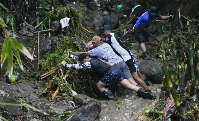 Volunteers and rescuers move debris as they search for bodies of missing residents believed to be buried under a landslide caused by heavy rains from Tropical Storm Yagi, locally called Enteng, swept their homes in San Luis village, Antipolo city, Rizal province, Philippines on Tuesday, Sept. 3, 2024. (AP Photo/Aaron Favila)