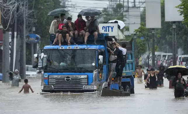 Commuters ride on top of a truck to avoid flood waters caused by heavy rains from Tropical Storm Yagi, locally called Enteng, on Monday, Sept. 2, 2024, in Cainta, Rizal province, Philippines. (AP Photo/Aaron Favila)