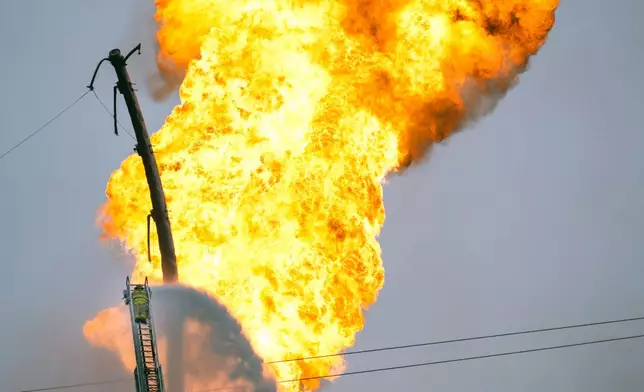 A firefighter directs water toward a pipeline fire in La Porte, Texas, Monday, Sept. 16, 2024. (Brett Coomer/Houston Chronicle via AP)