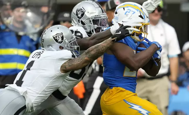 Los Angeles Chargers running back J.K. Dobbins, right, runs against Las Vegas Raiders safety Marcus Epps, left, and cornerback Nate Hobbs during the second half of an NFL football game, Sunday, Sept. 8, 2024, in Inglewood, Calif. (AP Photo/Ashley Landis)