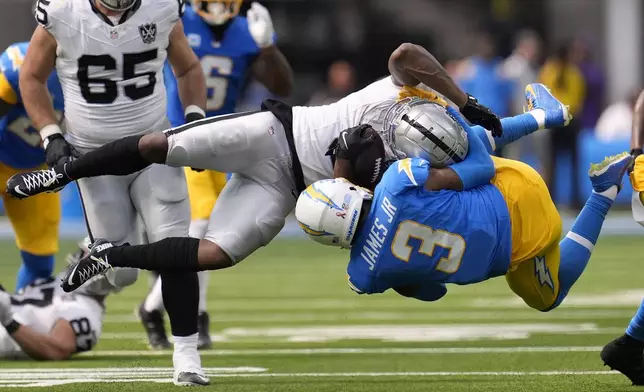 Las Vegas Raiders running back Zamir White, foreground top, is tackled by Los Angeles Chargers safety Derwin James Jr. during the second half of an NFL football game, Sunday, Sept. 8, 2024, in Inglewood, Calif. (AP Photo/Marcio Jose Sanchez)