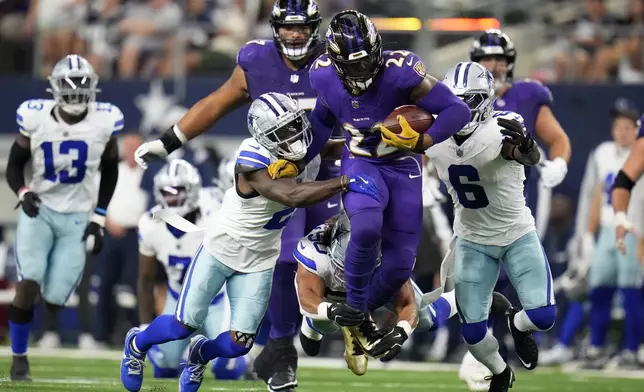 Baltimore Ravens running back Derrick Henry (22) runs the ball as Dallas Cowboys' Jourdan Lewis (2), Eric Kendricks, bottom, and Donovan Wilson (6) attempt to make the stop in the first half of an NFL football game in Arlington, Texas, Sunday, Sept. 22, 2024. (AP Photo/Julio Cortez)