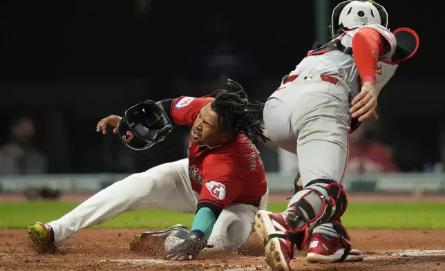 Cleveland Guardians' Jose Ramirez, left, scores safely behind Cincinnati Reds catcher Tyler Stephenson, right, in the fifth inning of a baseball game in Cleveland, Tuesday, Sept. 24, 2024. (AP Photo/Sue Ogrocki)