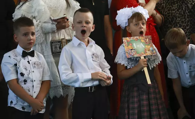 First graders yawn as they attend a ceremony marking the start of classes at a school as part of the traditional opening of the school year known as "Day of Knowledge" in Makiivka, Russian-controlled Donetsk region, eastern Ukraine, on Monday, Sept. 2, 2024. (AP Photo/Alexei Alexandrov)