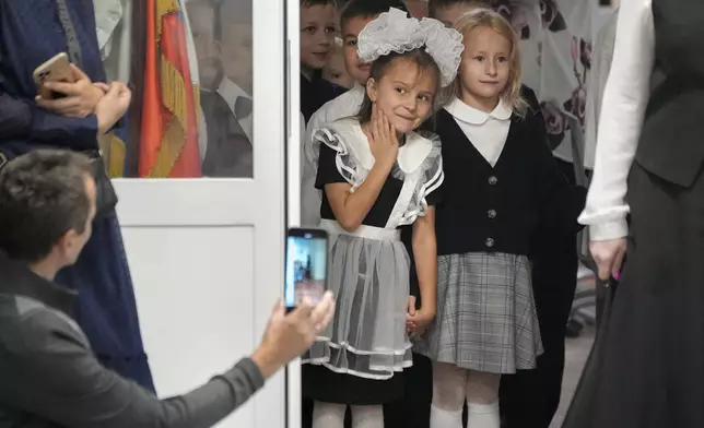 First graders enter a school to take part in a ceremony marking the start of classes as part of the traditional opening of the school year known as "Day of Knowledge" in St. Petersburg, Russia, Monday, Sept. 2, 2024. (AP Photo/Dmitri Lovetsky)