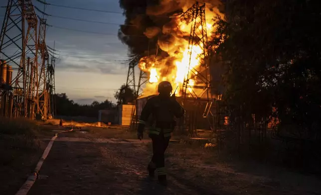 A Ukrainian firefighter talks on the radio while he works to extinguish the fire on the site of an electrical substation that was hit by Russian strike in Dnipropetrovsk region, Ukraine, Monday, Sept. 2, 2024. (AP Photo/Alex Babenko)