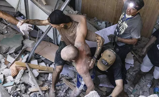 People help an injured man walk out of rubble at a sports facility destroyed after a Russian attack in Kharkiv, Ukraine, Sunday, Sept. 1 2024. (AP Photo/Yevhen Titov)