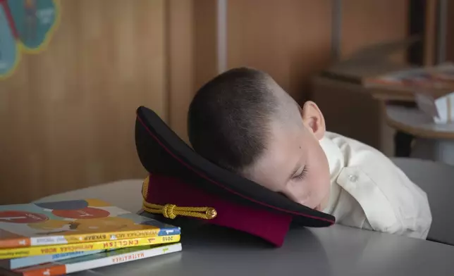 A young cadet takes a nap at the first lesson in a cadet lyceum on the first day at school in Kyiv, Ukraine, Monday, Sept. 2, 2024. Children and students went to school despite the fact that Kyiv was hit by massive Russian missile barrage early in the morning, causing fires, damaged buildings and infrastructure objects. (AP Photo/Efrem Lukatsky)