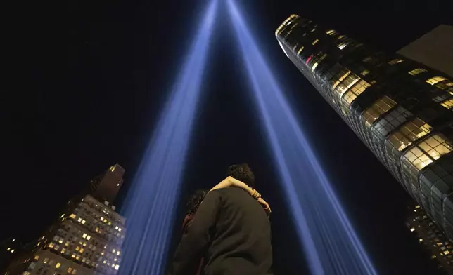 People embrace while The Tribute in Light is illuminated in the sky on the 23rd anniversary of the Sept. 11, 2001 attacks, Wednesday, Sept. 11, 2024, in New York. (AP Photo/Yuki Iwamura)