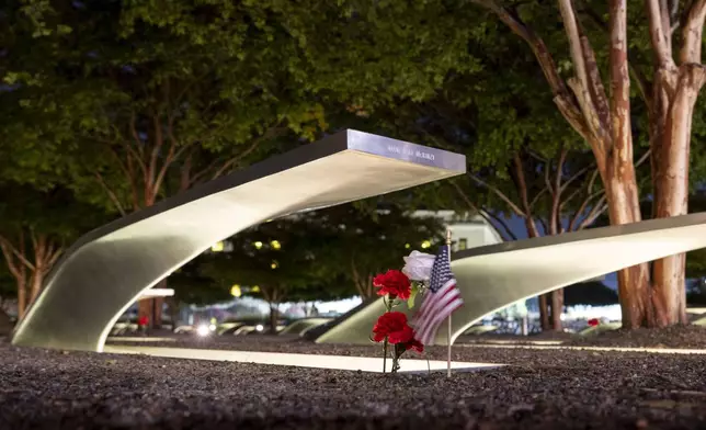 Flowers and a flag adorn one of the memorial benches outside the Pentagon before the start of a dawn 9/11 remembrance ceremony on Wednesday, Sept. 11, 2024 in Washington. (AP Photo/Kevin Wolf)