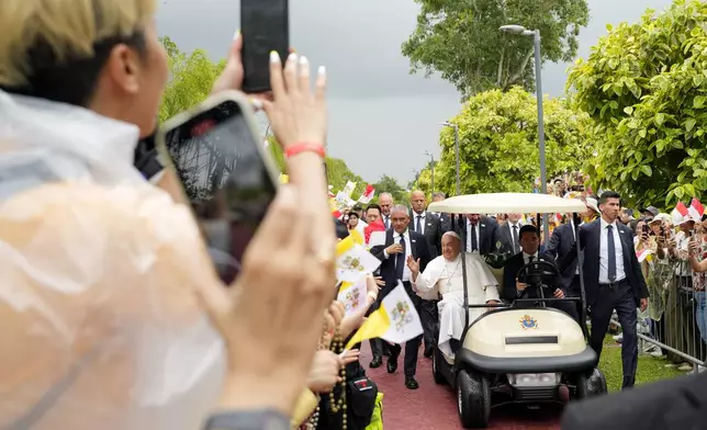 Pope Francis travels in a buggy as he greets the volunteers on his arrival in Singapore, Wednesday, Sept. 11, 2024. (AP Photo/Vincent Thian)