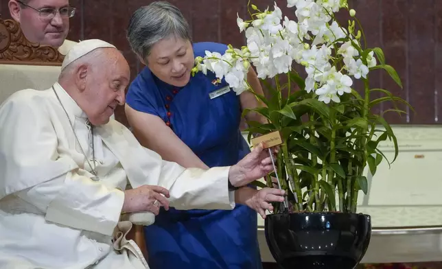 Chief Executive Officer of the Singapore's National Parks Board Hwang Yu-Ning presents Pope Francis with a 'Dendrobium His Holiness Pope Francis', a specially bred orchid variety named after him at the Parliament House in Singapore, Thursday, Sept. 12, 2024. Pope Francis flew to Singapore on Wednesday for the final leg of his trip through Asia, arriving in one of the world's richest countries from one of its poorest after a record-setting final Mass in East Timor. (AP Photo/Gregorio Borgia)