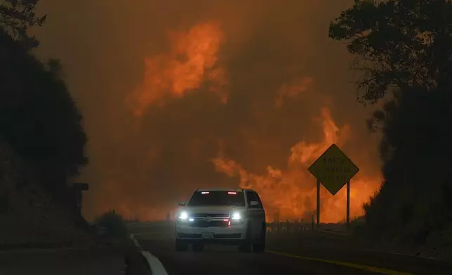 The Line Fire jumps highway 330 as an emergency vehicle is driven past Saturday, Sept. 7, 2024, near Running Springs, Calif. (AP Photo/Eric Thayer)