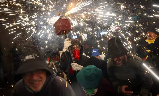 People dance as revelers hold fireworks as they take part in a "Correfoc", or run with fire, party in Barcelona, Spain, Sunday, Sept. 15, 2024. (AP Photo/Emilio Morenatti)