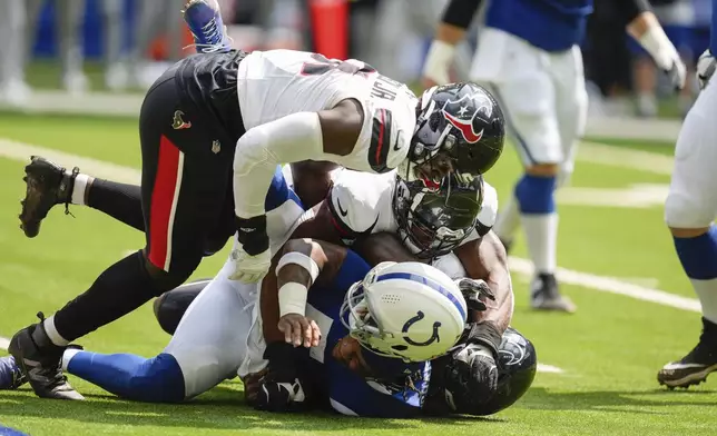 Indianapolis Colts quarterback Anthony Richardson (5) loses his helmet as he is sacked by Houston Texans defensive end Mario Edwards Jr. (97) during the first half of an NFL football game, Sunday, Sept. 8, 2024, in Indianapolis. (AP Photo/Darron Cummings)